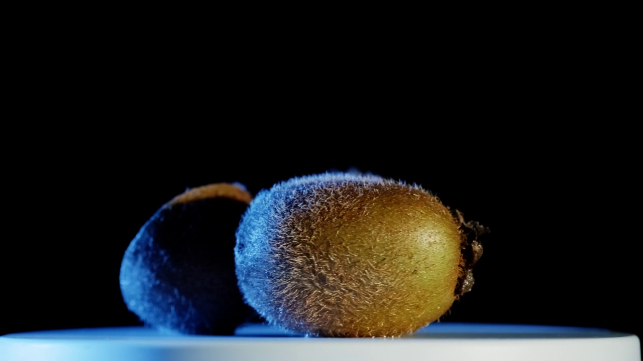 近景拍摄的切片猕猴桃旋转在黑暗的背景。视频素材