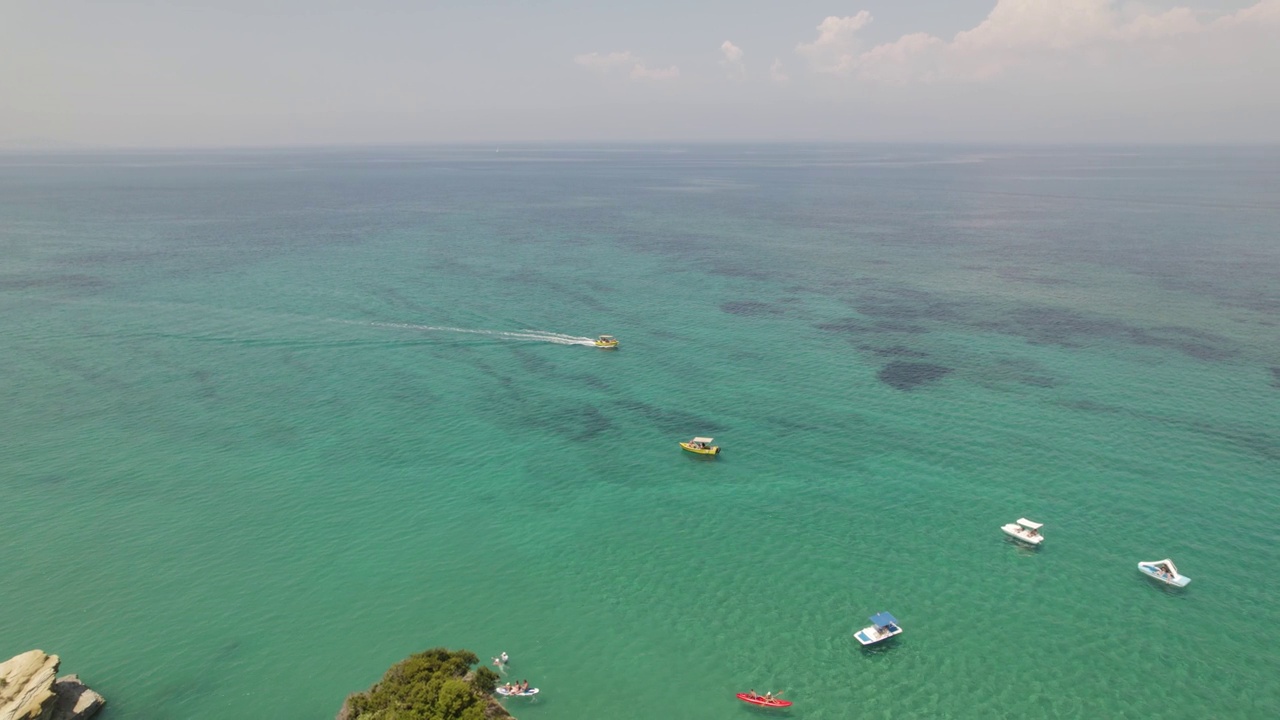 在希腊科孚岛西达里海岸线上的绿松石海景与旅游船的空中轨道视频下载