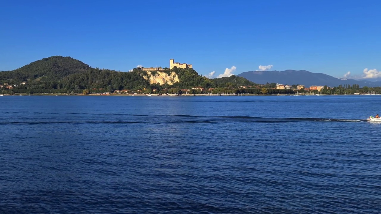 小汽艇在意大利马乔雷湖平静的湖水中航行，背景是安格拉城堡。慢动作视频素材