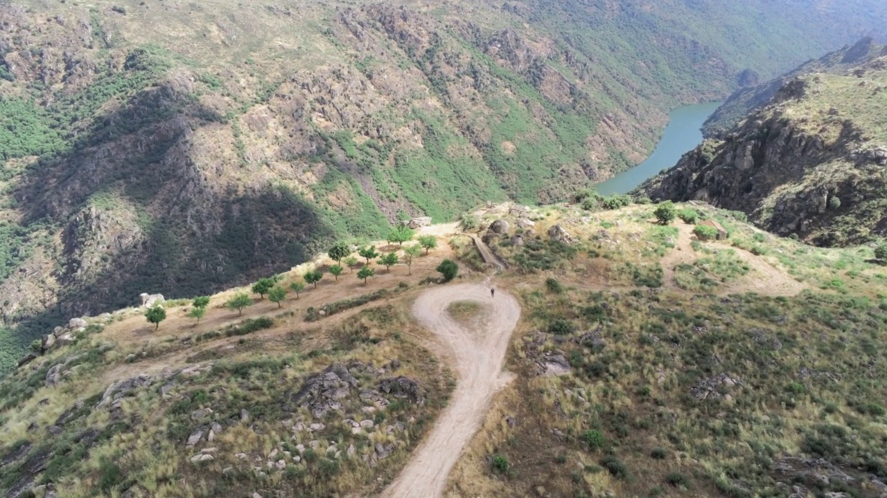 鸟瞰山顶、森林和山顶的道路，在一个阳光明媚的日子里，有一条河流在流动视频素材