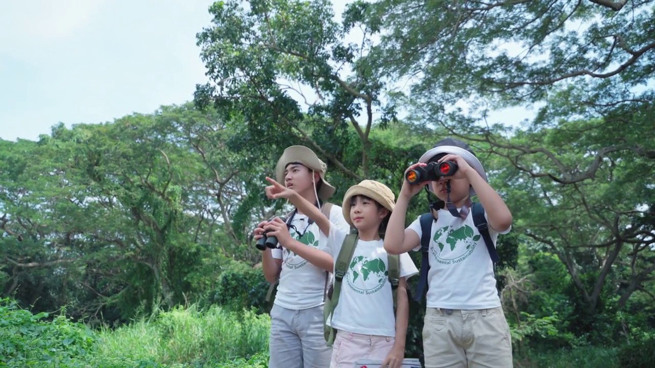 冒险和探索的一个男孩和女孩亚洲年龄6-12岁有一个自然的旅程，实地考察休闲活动，在热带森林用望远镜看野生动物。视频下载