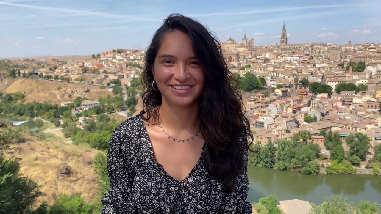 Young woman smiling with the village of España Toledo in the background视频下载