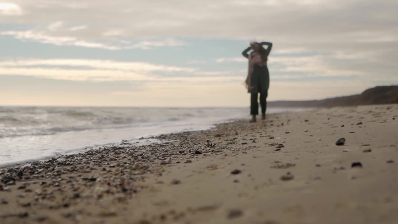 快乐的混合民族妇女跑在沙滩上的背景散景。俏皮的微笑亚洲女性通风的头发吹在风。低角度宽梦幻电影慢动作120帧/秒。视频素材