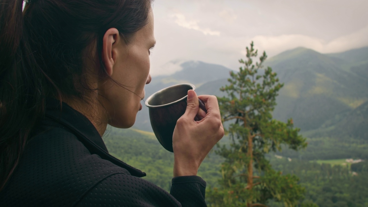 假日旅行中，徒步旅行的妇女在山顶上喝热茶或咖啡视频素材