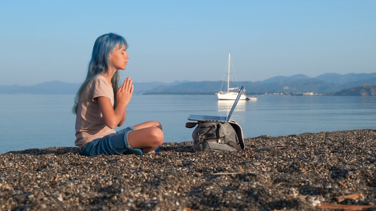 女孩坐在岸上运动呼吸。视频素材