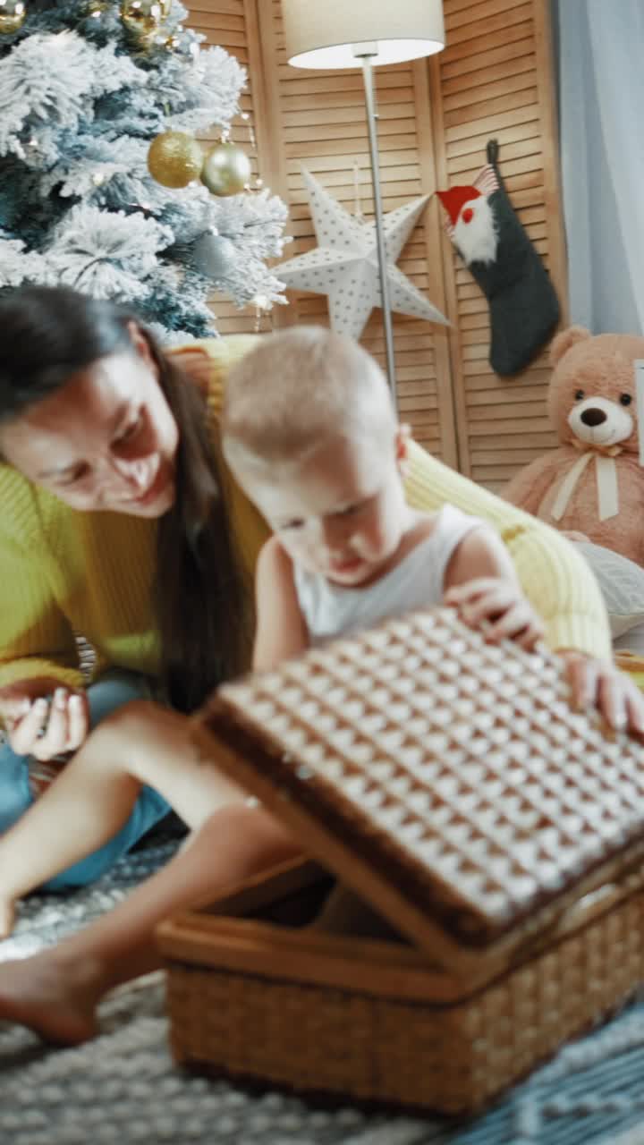 垂直拍摄的年轻母亲和幼小的婴儿在圣诞树旁和宠物玩耍视频素材