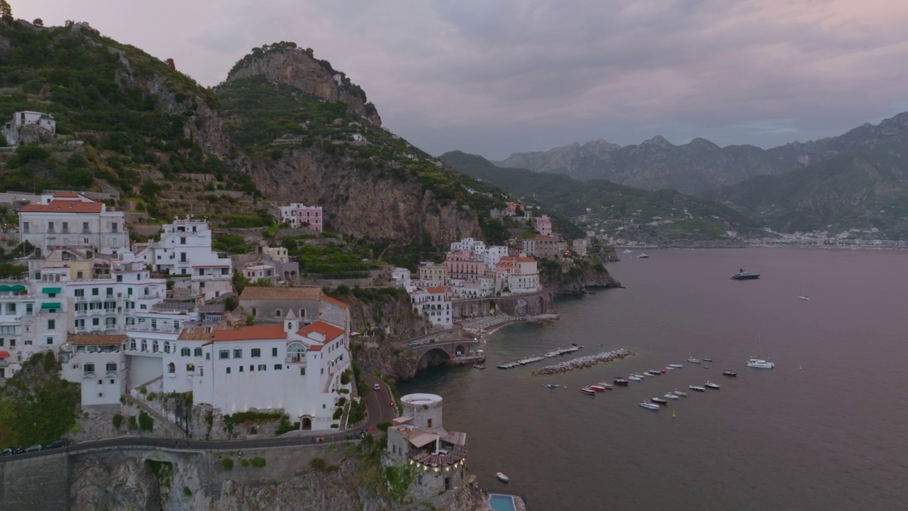 黄昏时分在地中海旅游目的地的建筑物周围飞行。沿海斜坡上的建筑物和道路。意大利阿视频素材