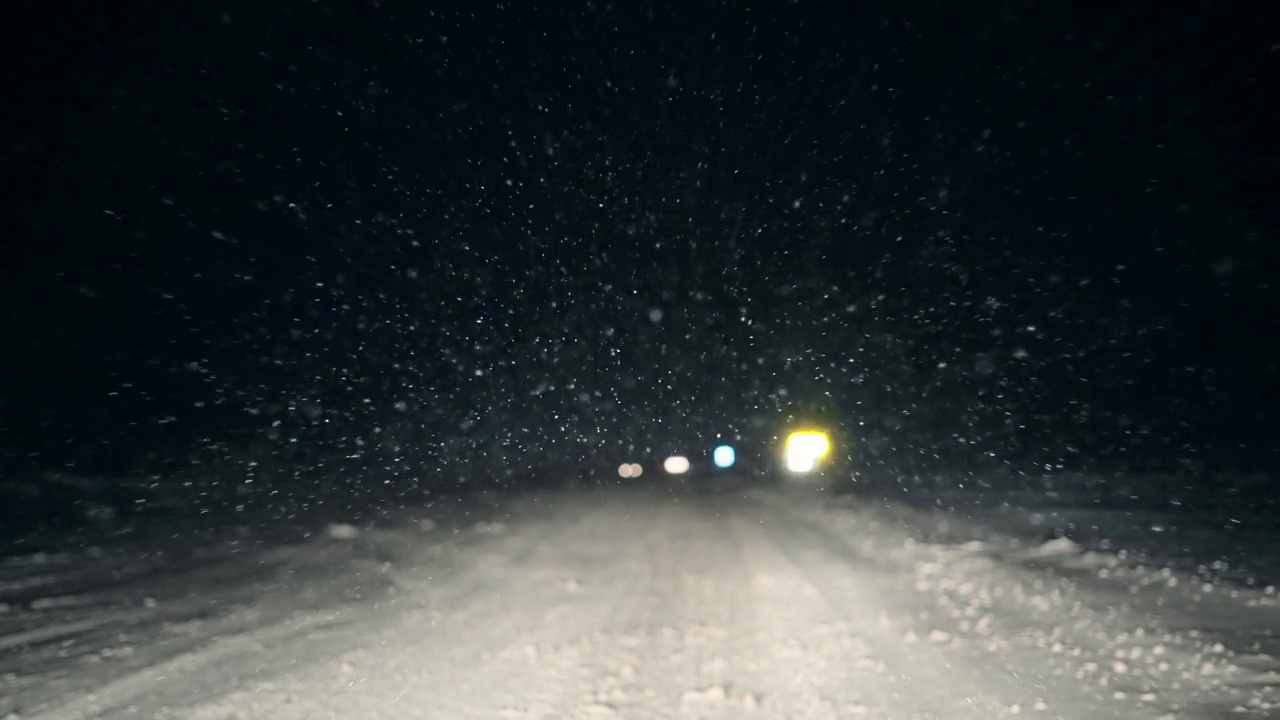 夜间在山区乡村道路上行驶，雪花落在汽车挡风玻璃上视频素材