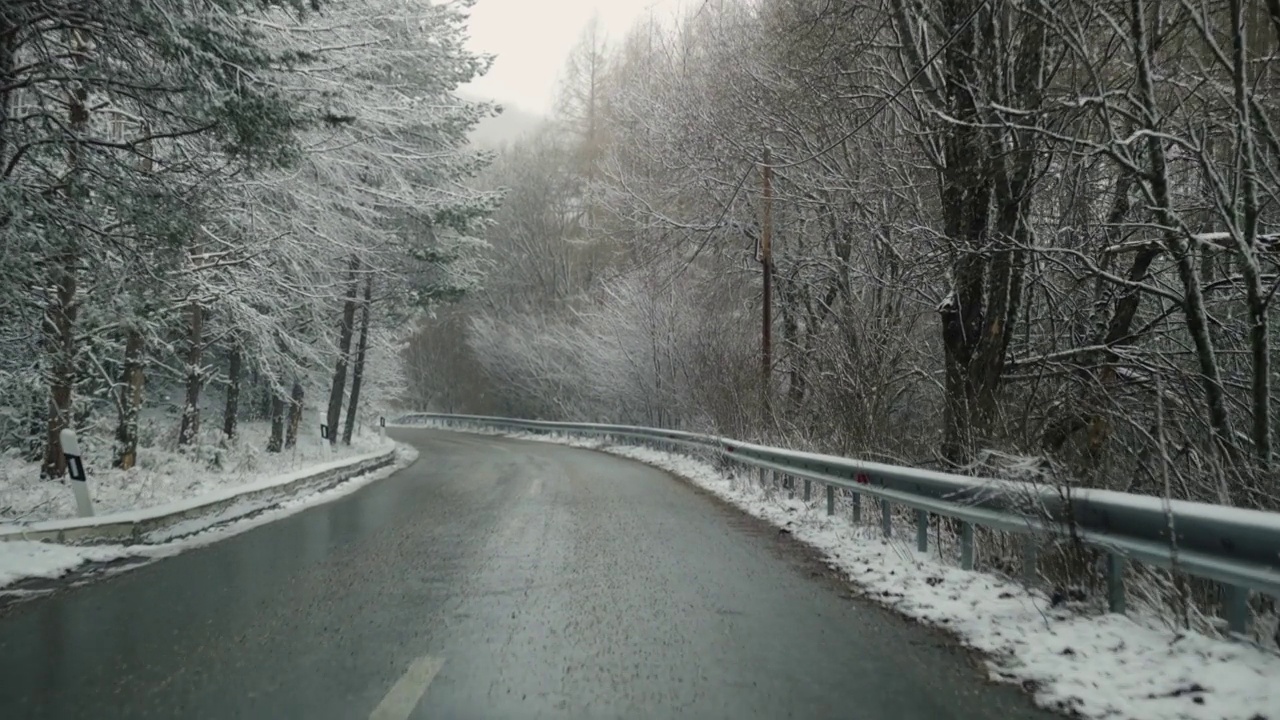 在冰天雪地的山林乡村道路上开车的Pov视频素材