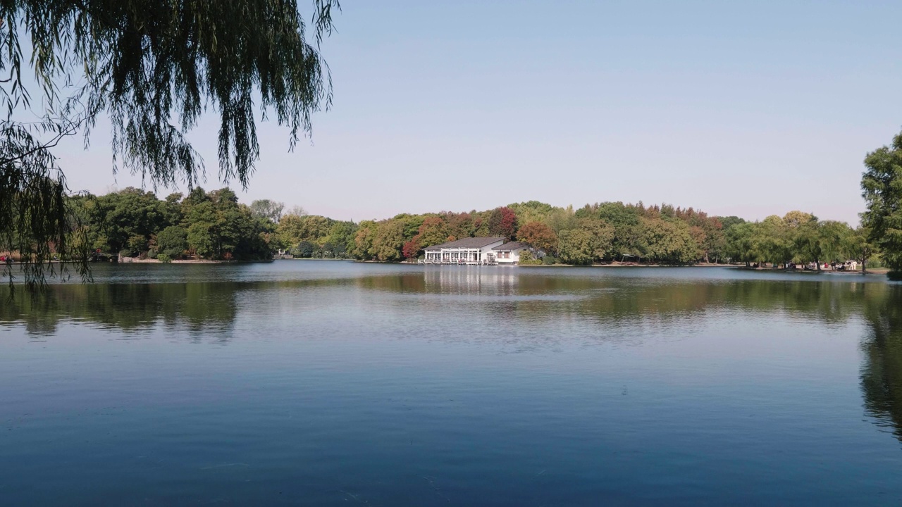 阳光明媚的秋日，上海共青森林公园宁静的风景，彩色的树木与蓝天和湖面的倒影，4k慢镜头。视频素材