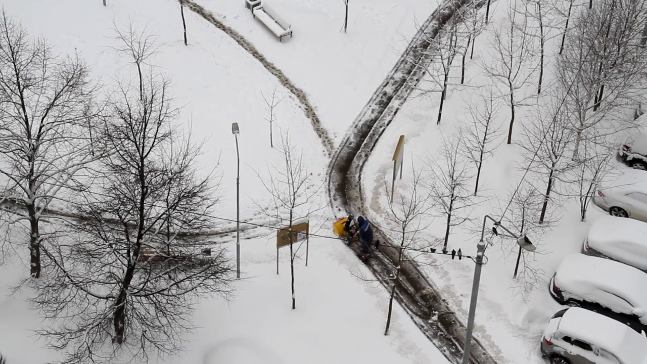 工人用吹雪机在城市院子里除雪视频素材