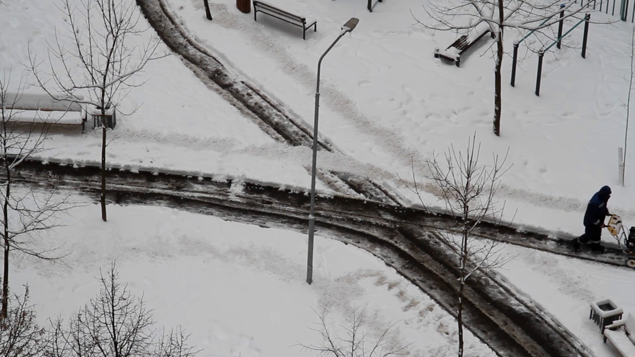 工人用吹雪机在城市院子里除雪视频素材