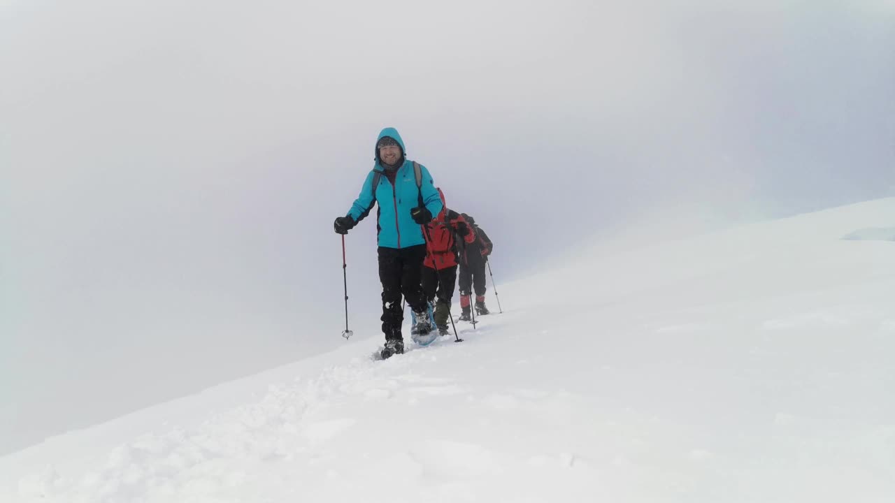 背包和雪鞋的徒步旅行者在冬季徒步旅行中行走。视频素材