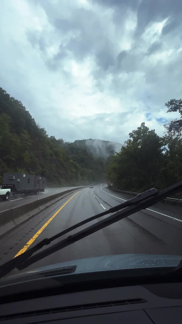 垂直视频汽车视角拍摄在雨中沿着田纳西州蓝岭山脉绿树成荫的40号州际公路行驶，在一个戏剧性的多云天空下视频素材