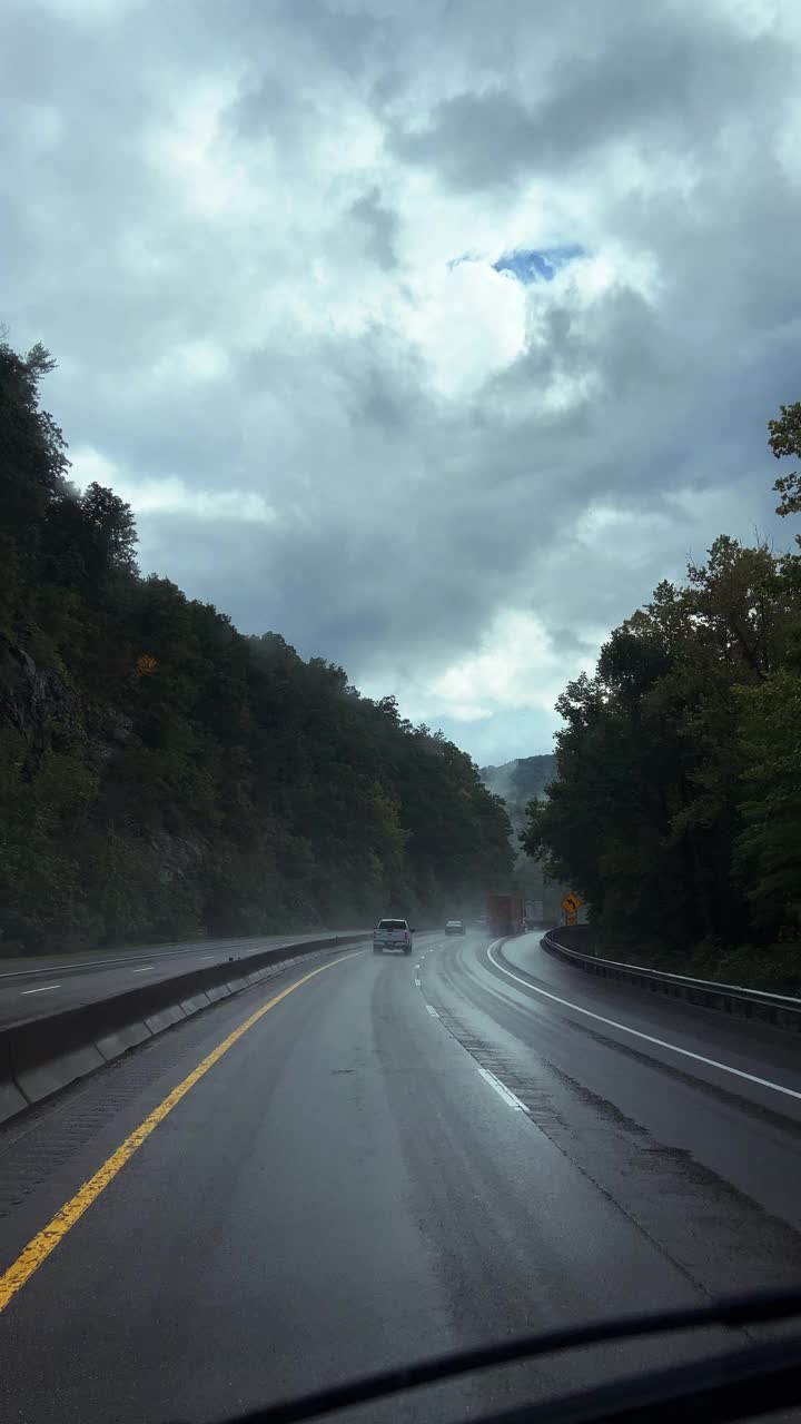 垂直视频汽车视角在雨中通过雨刷拍摄，当时行驶在田纳西州蓝岭山脉树木成行的40号州际公路上，天空阴云密布视频素材