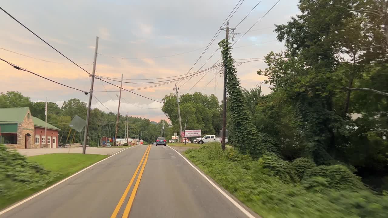 在日落时分的阴天，沿着绿树成荫的夏洛特高速公路行驶，路过北卡罗来纳州费尔维尤的一些企业视频素材