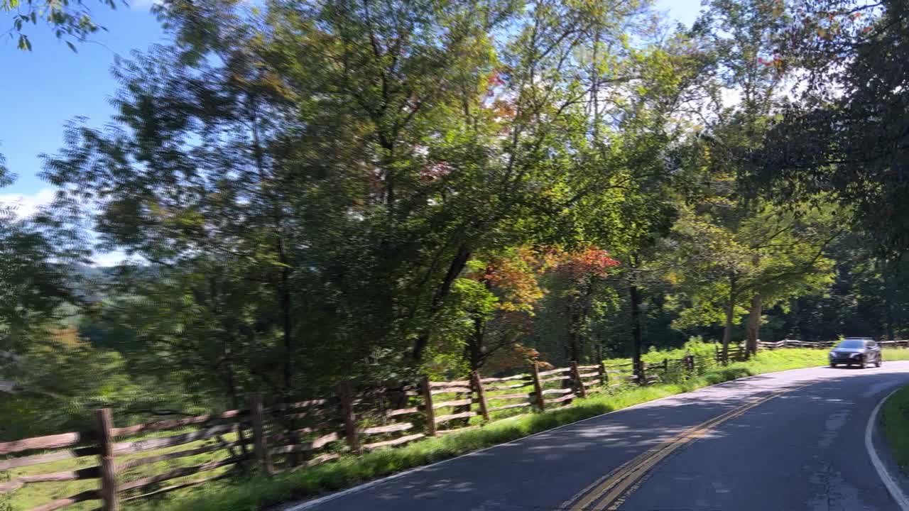 在阳光明媚的日子里，在北卡罗来纳州美景镇的一条蜿蜒的道路上行驶的汽车视角镜头视频素材