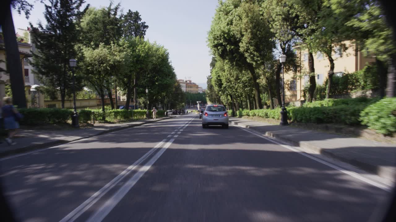 PROCESS PLATE STRAIGHT FORWARD OF CAR DRIVING ON TREE LINED ROAD. CAMERA APPROACHES PIAZZALE DI PORTA ROMANA TRAFFIC CIRCLE. PORTA ROMANA GATE VISIBLE. PISTOLETTOÕS DIETROFRONT STATUE VISIBLE视频素材