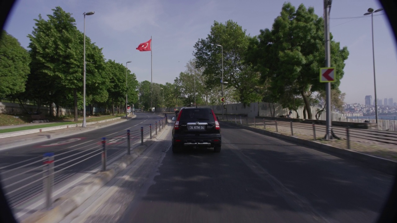 在肯尼迪大街或肯尼迪球童街上，紧跟警车和警用摩托车的汽车正前方的流程牌。可见的马马拉海。可能是沿海公路。海边可见的人行道或小路视频素材