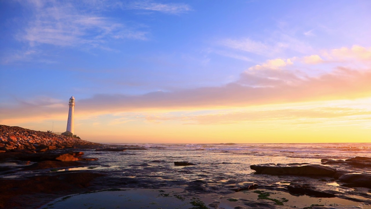 海滩上有海浪和灯塔，还有夕阳的天空视频素材