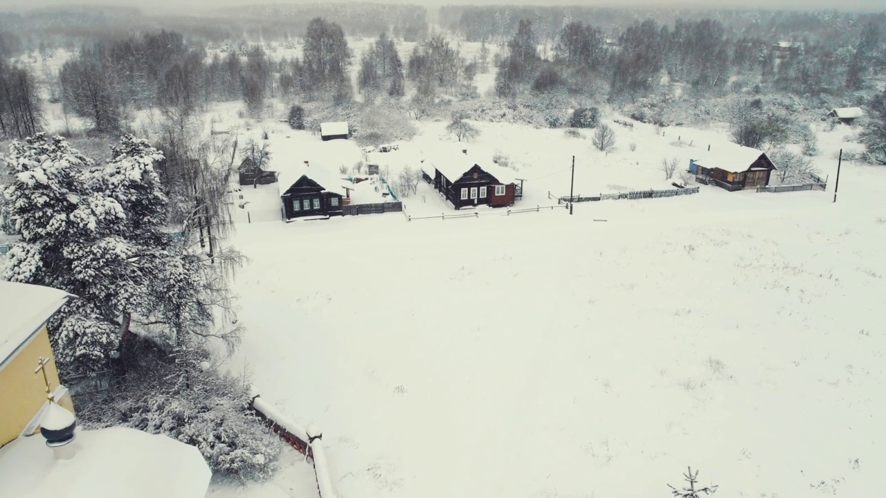 鸟瞰图，一个冬天下雪的村庄和一个教堂。视频素材