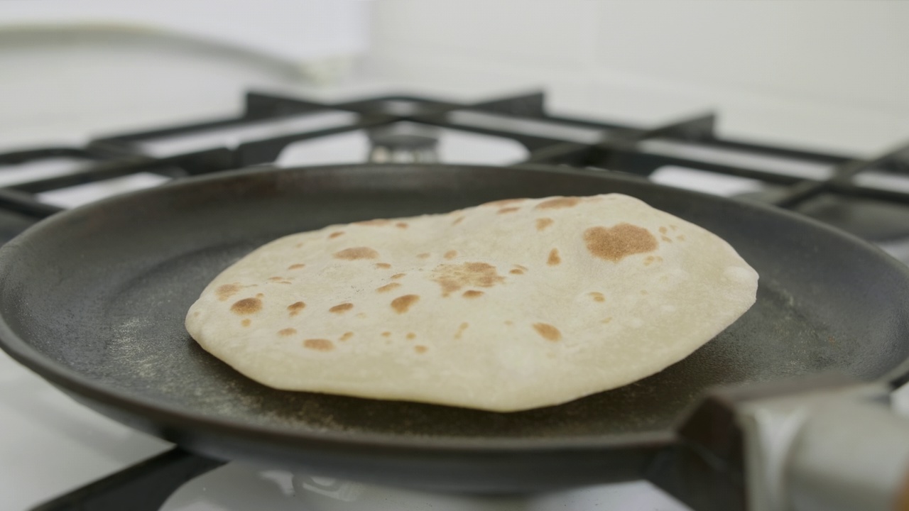 皮塔饼在热锅上烹饪，用肩胛骨翻转，时间流逝的视频视频素材