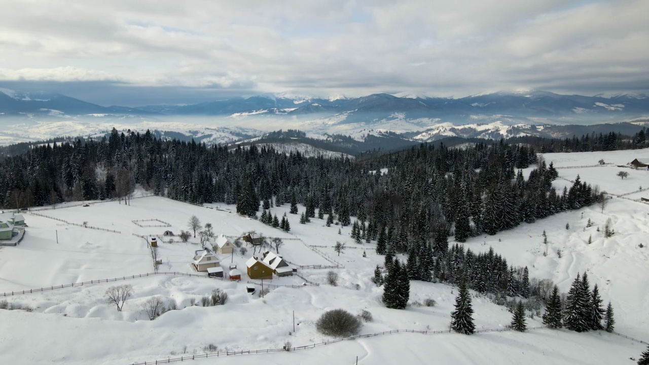 冬季景观，小村庄房屋之间的积雪覆盖的森林在寒冷的山区视频素材