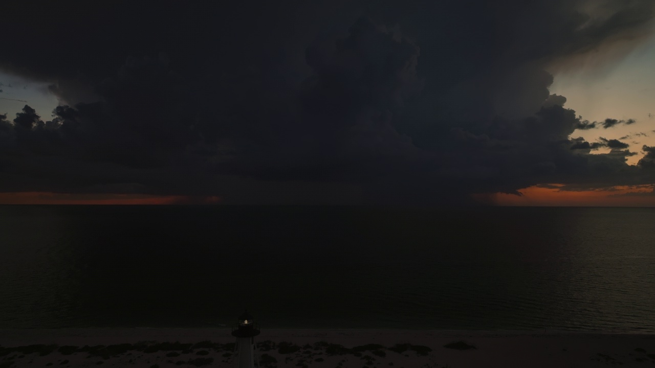 海岸上的白色灯塔，在暴风雨的夜晚闪烁着灯光，供商业船只航行。海面上有雷暴和闪电，对船只构成危险视频素材