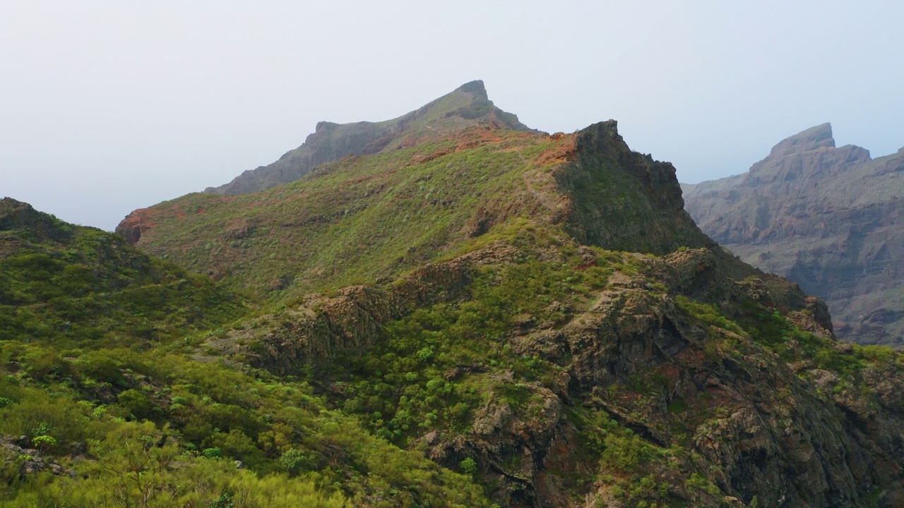 山岭绝壁，险峻峭壁。著名旅游村。西班牙加那利岛特内里费岛。壮观的鸟瞰图，小舒适的定居点在山的一侧马斯卡峡谷通向海洋。视频素材