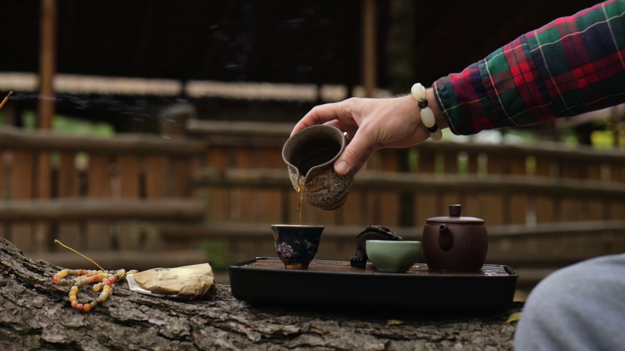 茶师把茶从陶壶倒进碗里。户外中国茶道视频下载