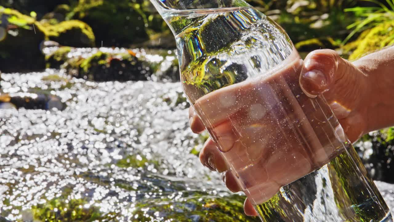 SLO MO Hand把水壶里的水倒进湍急的小溪视频素材