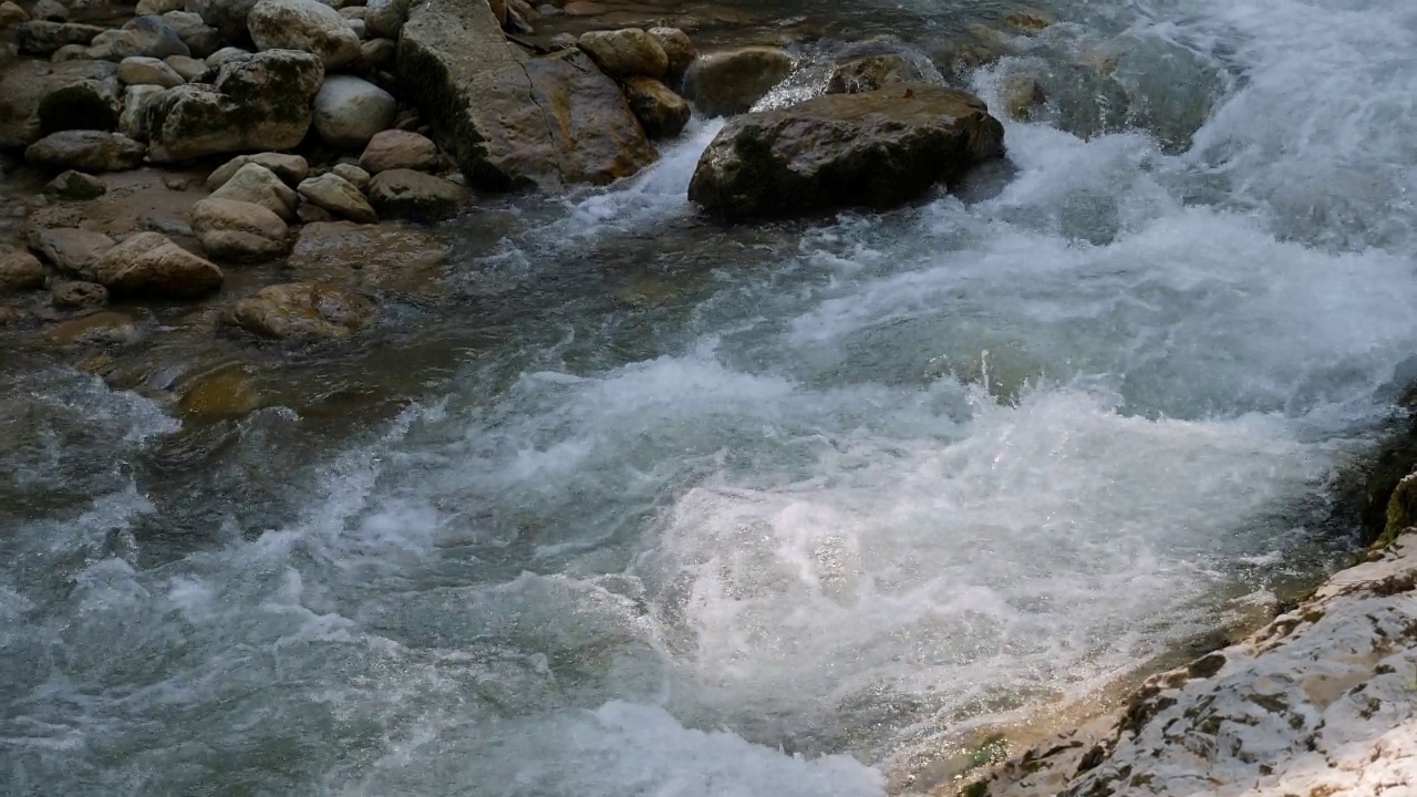 峡谷中的一条湍急的山河，水流过巨大的石头。视频素材