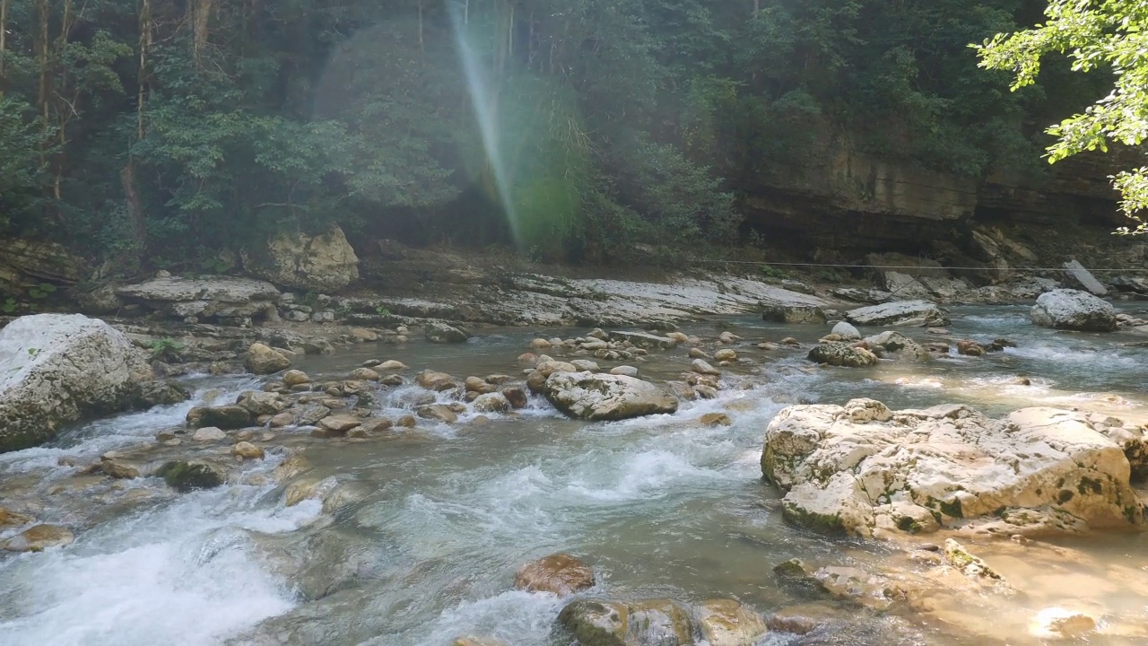 山快河在山间树木间受到阳光照射。视频素材