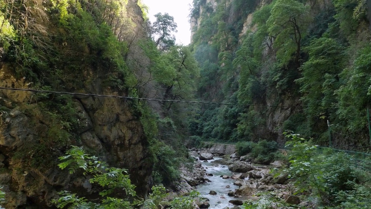 一个美丽的峡谷，有绿树和一条湍急的山间河流。视频素材