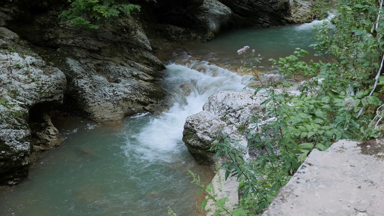 峡谷中的一条湍急的山河，水流过巨大的石头。视频素材
