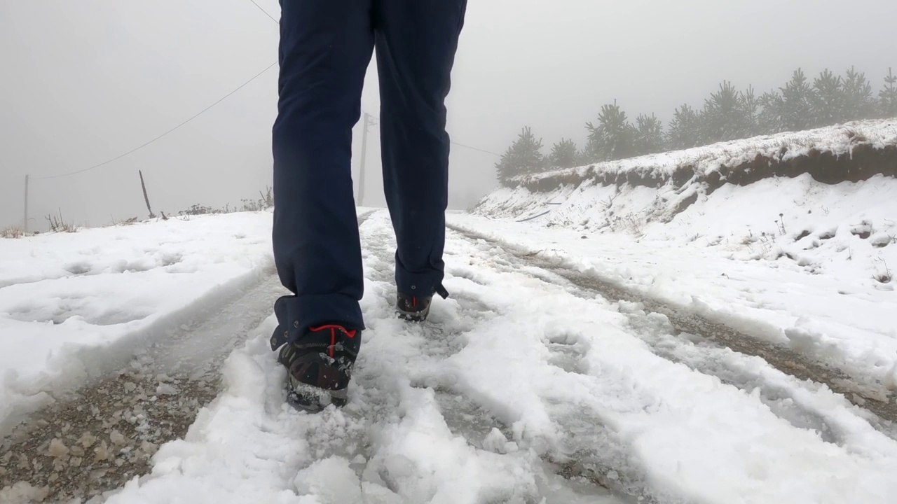 低视图迷路的徒步旅行者走在雪地上的道路上，在雪的轨道视频素材