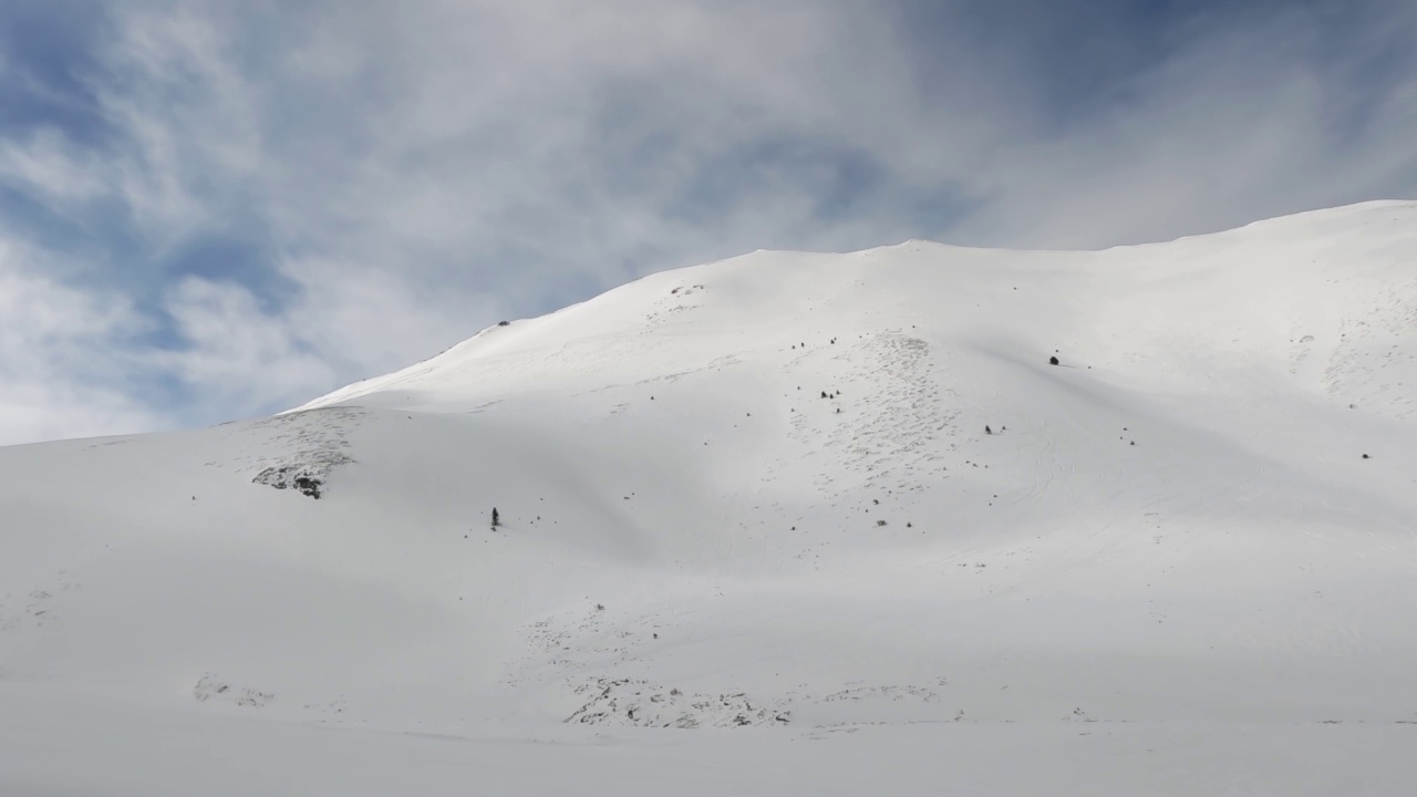 从移动的雪车，ratrack到令人惊叹的冬季景观的高海拔山脉山峰覆盖着新鲜的雪在阳光灿烂的日子视频素材