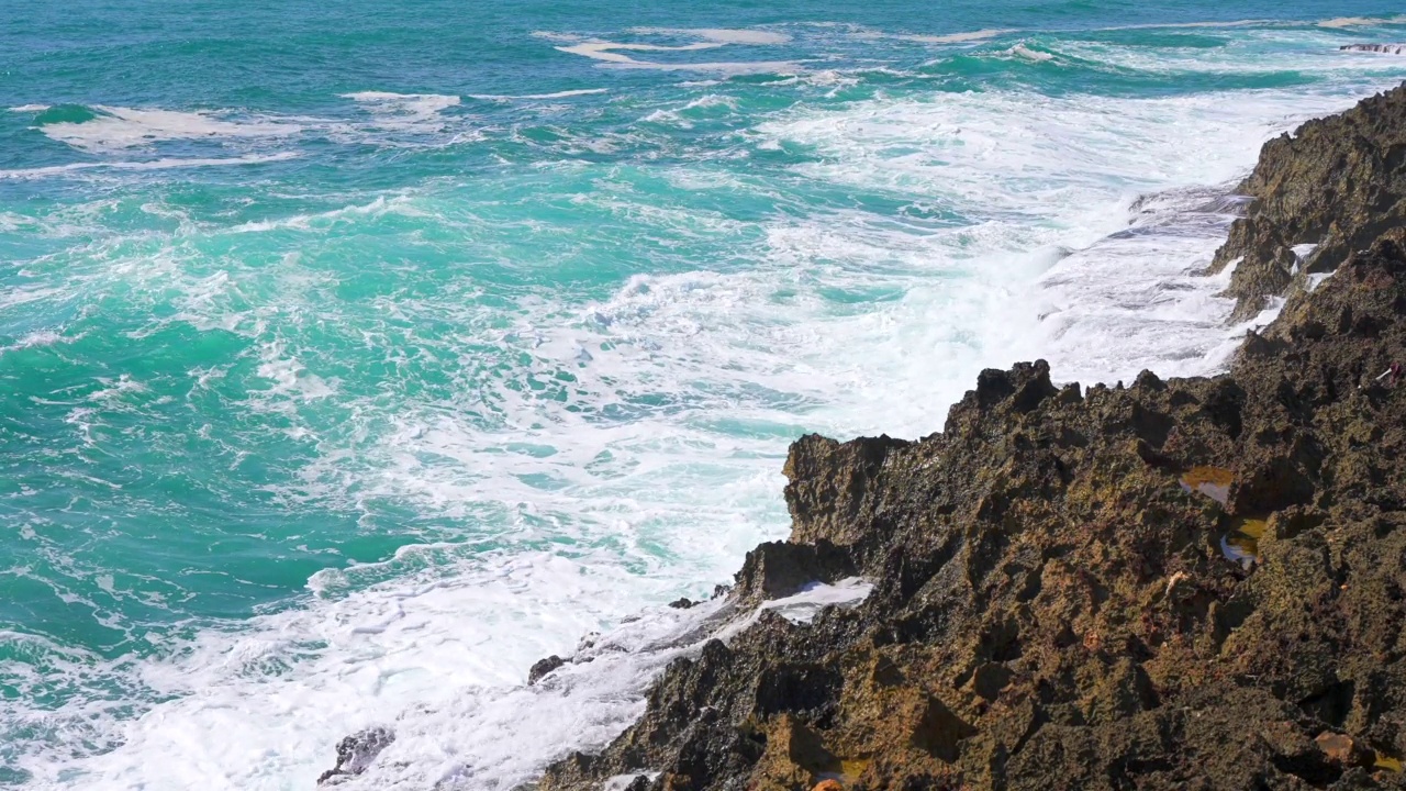 海浪拍打着岩石，蓝绿色的水在空中飞溅视频素材