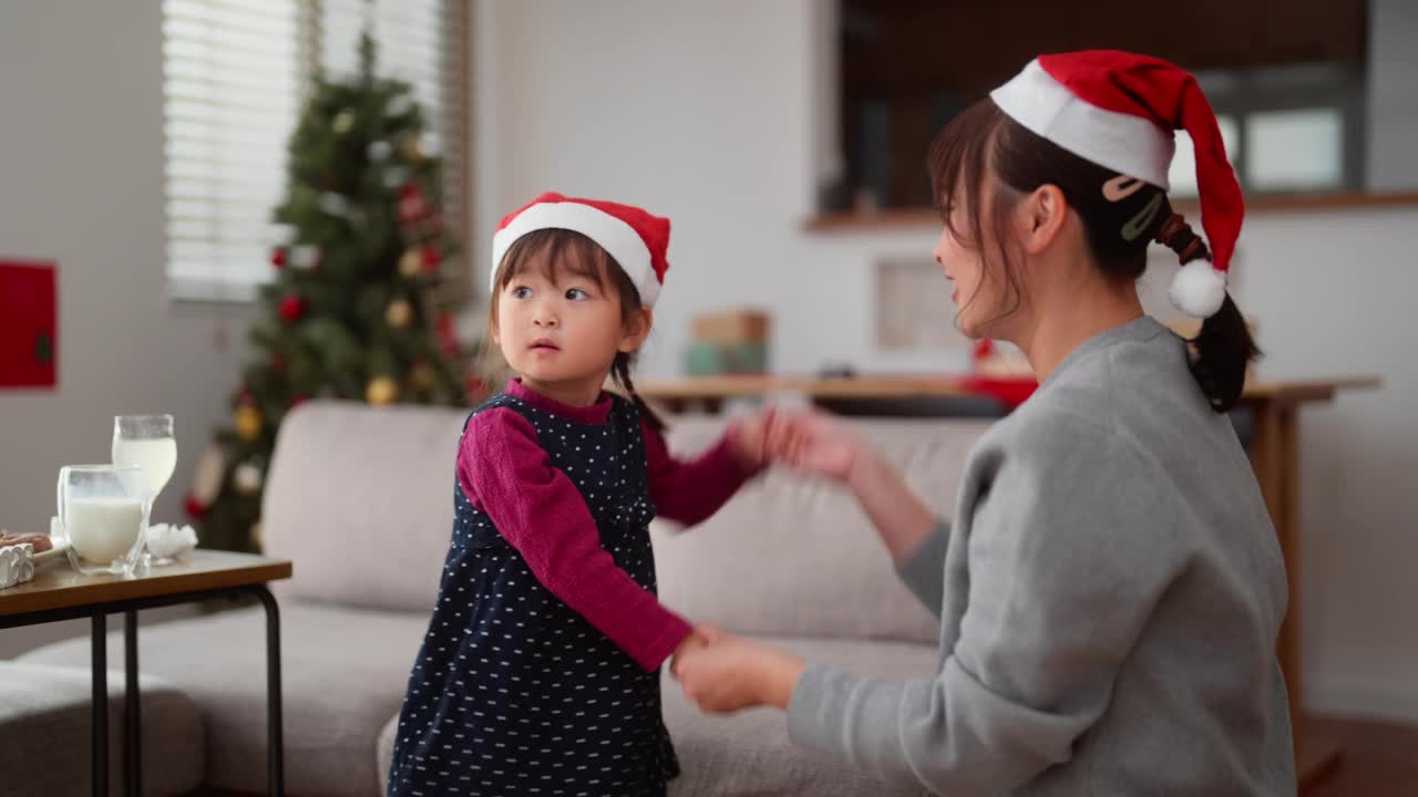 母亲和她学龄前的小女儿在家里的客厅里一起享受圣诞节和跳舞视频素材