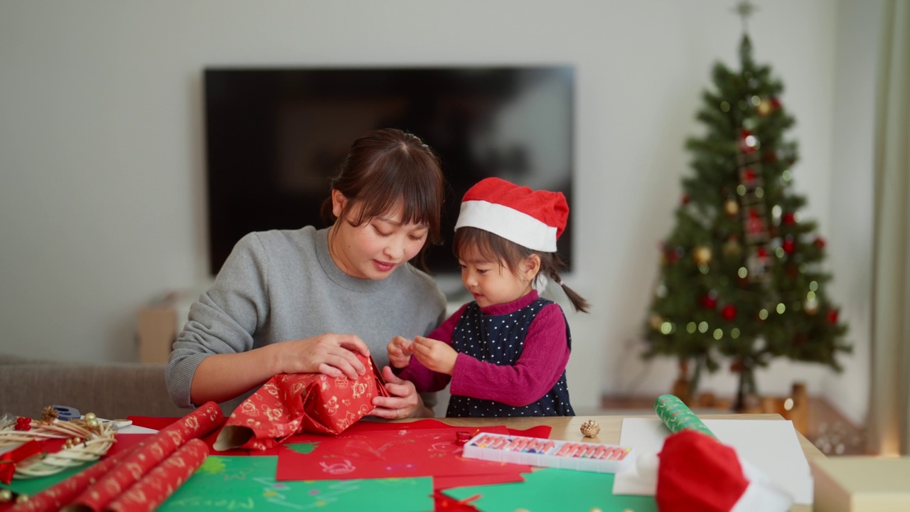 母亲和她学龄前的小女儿一起在家里的客厅里准备圣诞礼物视频素材