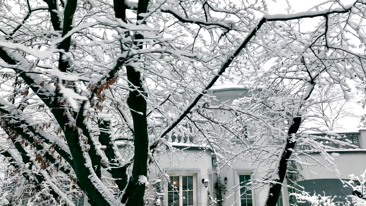 第一场雪和冬天的故事。房子和树都被雪覆盖了。冬天的私人住宅外观。视频素材