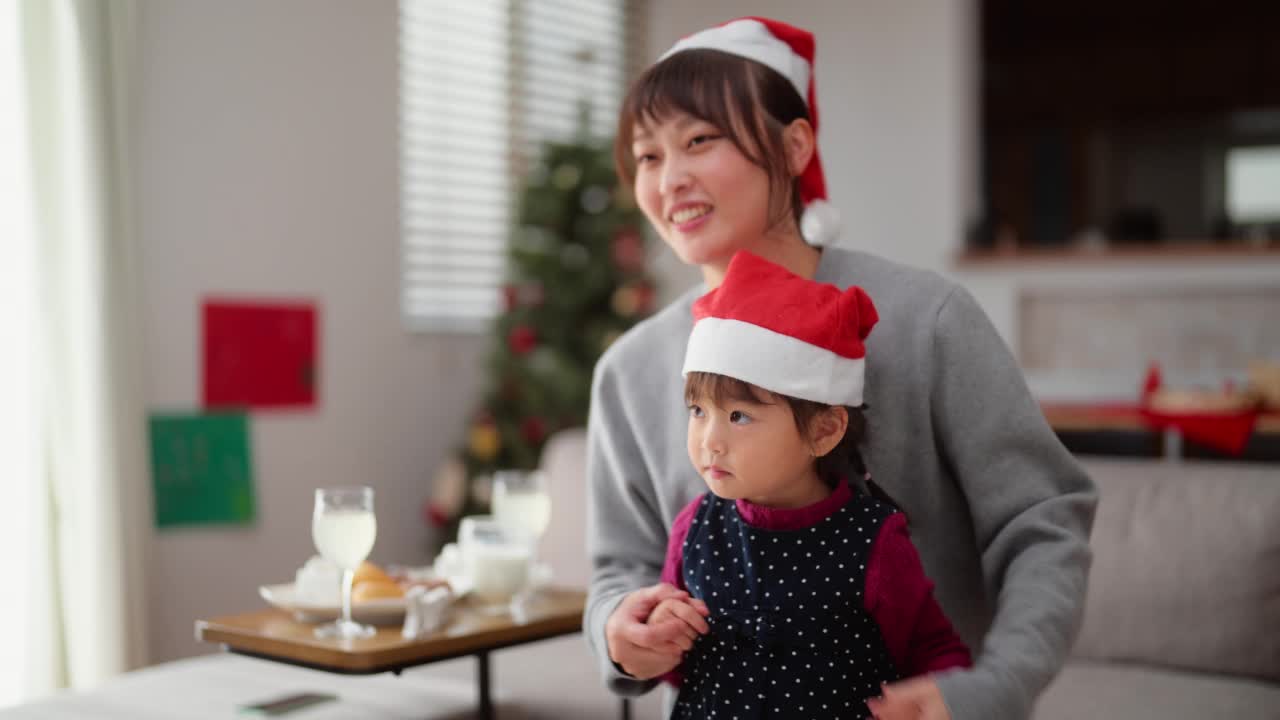 母亲和她学龄前的小女儿在家里的客厅里一起享受圣诞节和跳舞视频素材