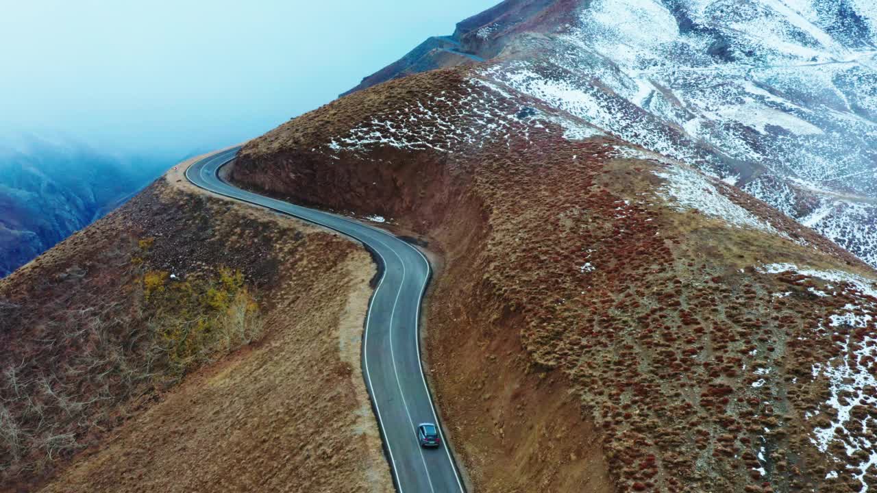 无人机跟踪在山峰上穿越雾霾的公路旅行视频素材