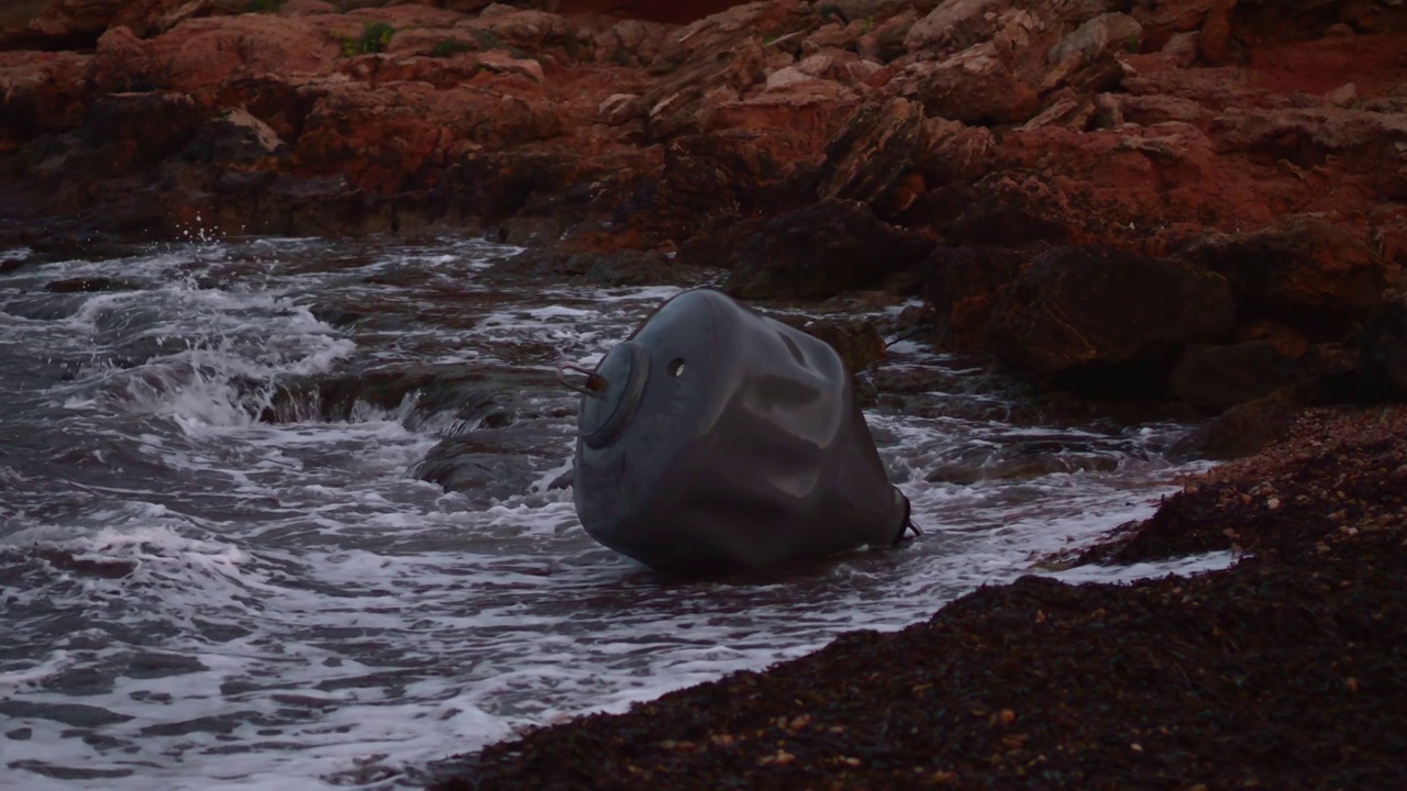 浮筒:被海水抛到岩石海滩上的大型海上浮标视频素材