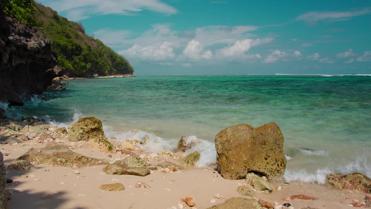 美丽的海岸线热带绿色碗海滩巴厘岛清澈蔚蓝的海洋和波浪的自然背景。岩石白沙海岸。视频素材