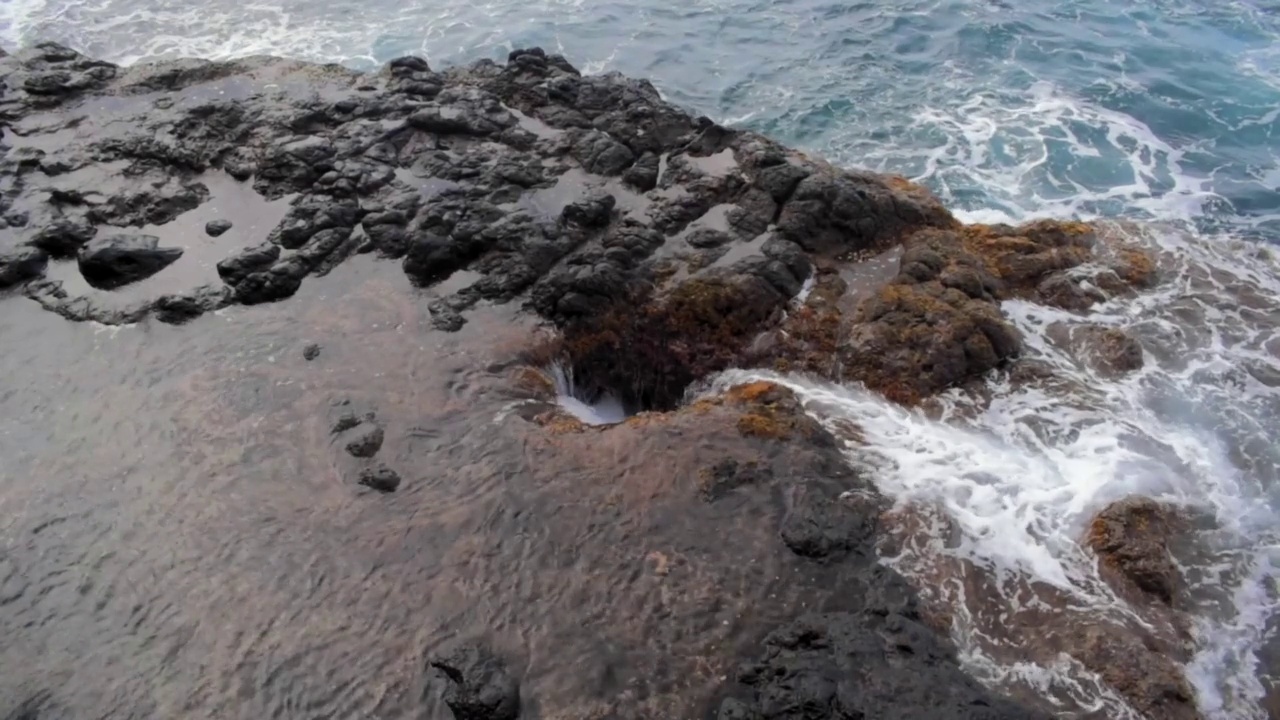 在法属波利尼西亚的Arahoho喷水孔，海浪撞击岩石海岸的空中慢动作视频素材