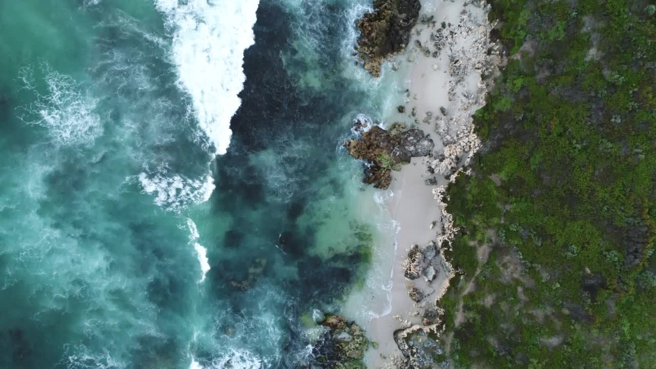 日光下，西澳大利亚伯恩斯海滩海浪拍打岩石的鸟瞰图视频素材