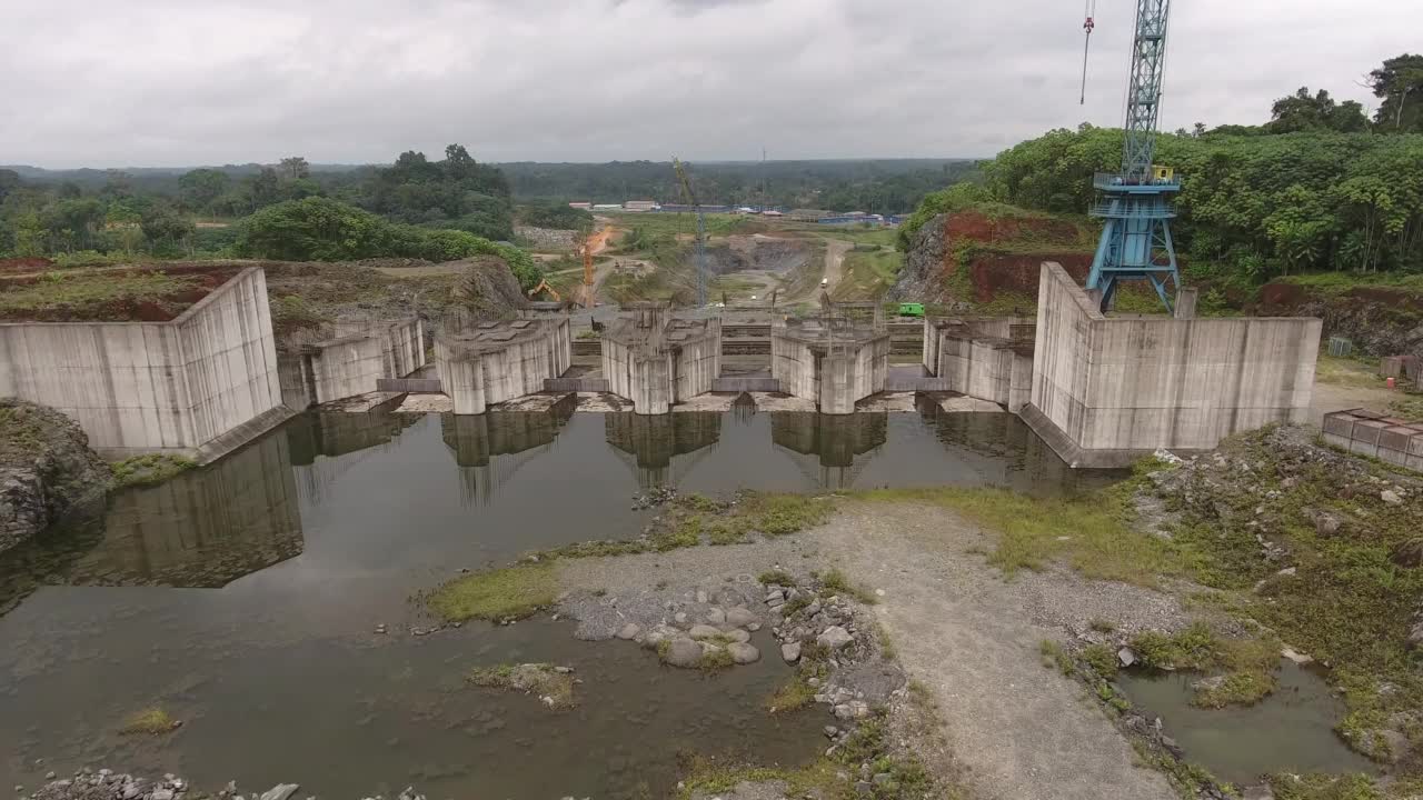 鸟瞰图。在热带丛林中修建水电站。河上水坝旁的建筑起重机。赤道几内亚，非洲。视频素材