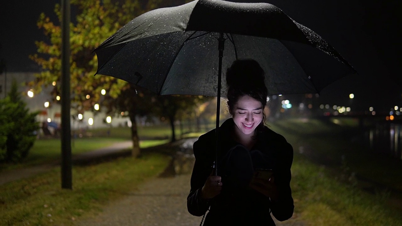 白人女孩在雨中行走时使用手机视频素材