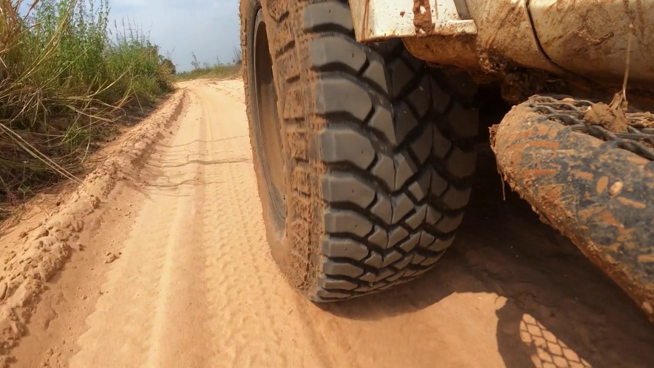 慢动作4x4越野皮卡车的车轮在土路上奔跑。越野卡车汽车车轮在肮脏的道路上移动，带着灰尘、干湿泥浆。观点四驱卡车轮胎旅行在偏僻的地方视频素材